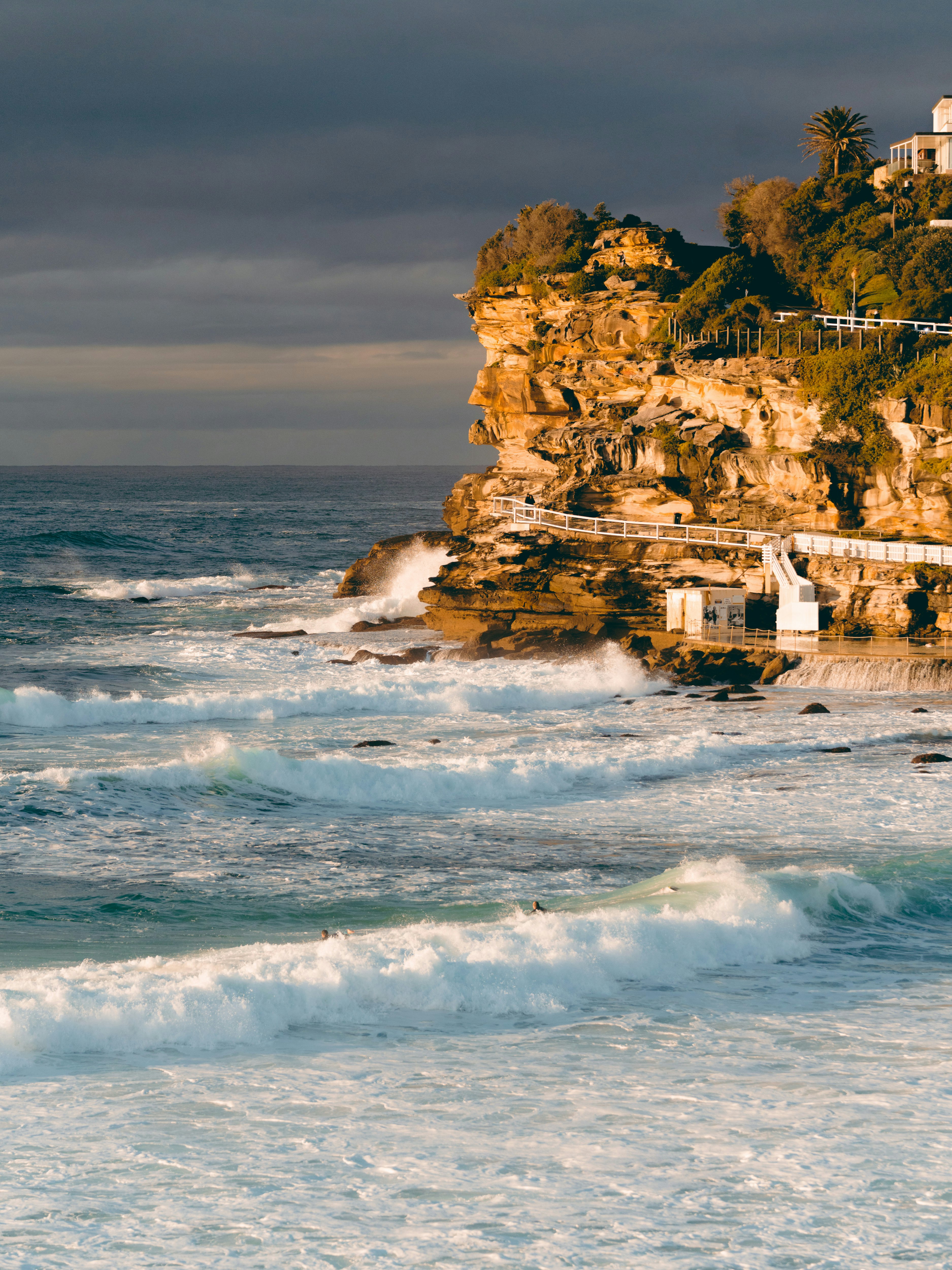 white concrete building near sea waves crashing on shore during daytime